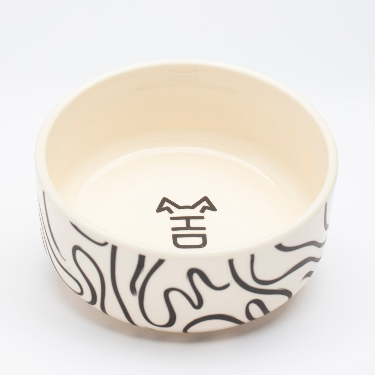 Front angle view of abstract black and white ceramic dog food bowl with minimalist design, bold black lines, and white glaze—ideal for pet food or as a decorative bowl.