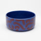 Front view of Flow ceramic dog bowl by Hot Doggies with red and blue pattern, made from durable ceramic, dishwasher safe, ideal for dog food and water.