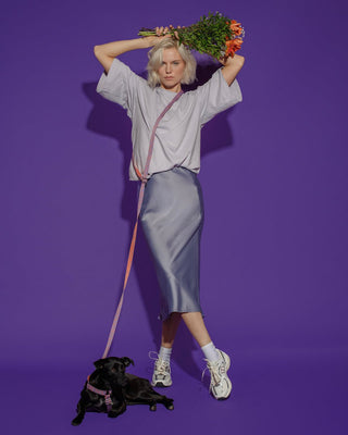 Hot Doggies Hands Free Dog Leash in Lily Coral – adjustable and eco-friendly, styled with fashion model holding flowers and black dog on vibrant purple background, perfect for dogs up to 22kg.