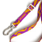 Purple and yellow patterned dog leash with a silver clip on a white background.