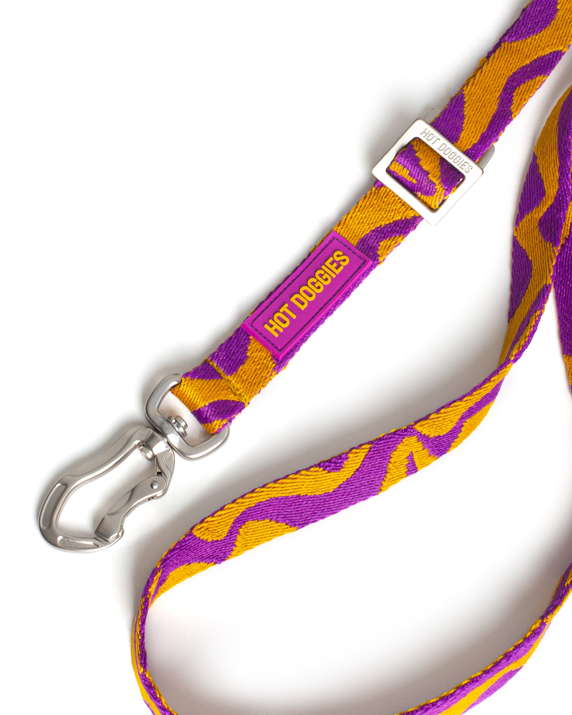 Purple and yellow patterned dog leash with a silver clip on a white background.