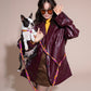 Woman in a burgundy leather jacket holding a small black and white dog on a BONNY PLUM HANDS-FREE LEASH against a beige background.