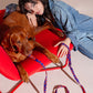 Woman lying on a red chair with a brown dog.