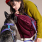 Woman in a red beret and green sweater interacting with a dog on a beige background.