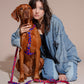 Woman with a dog wearing a colorful HARNESS ROCKY ELECTRIC on a beige background.